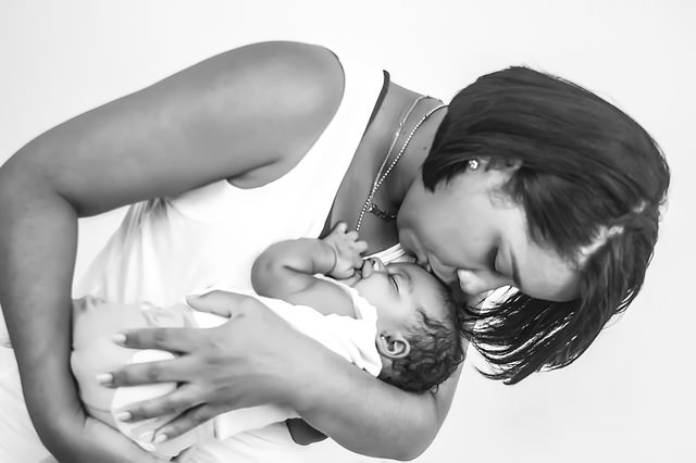 Kobieta całuje niemowlę, które trzyma na rękach