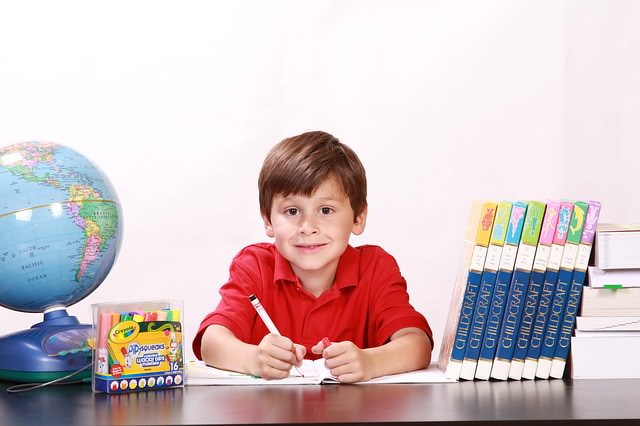 Uśmiechnięte dziecko uczy się przy biurku