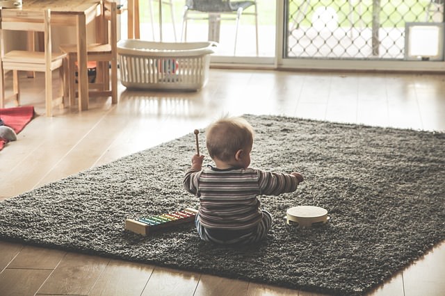 Dziecko siedzące na dywanie i grające