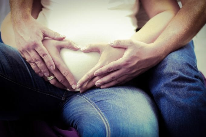 Kobieta w ciąży i mężczyzna z rękami na brzuchu