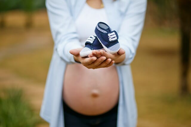 kobieta w ciąży trzyma buciki